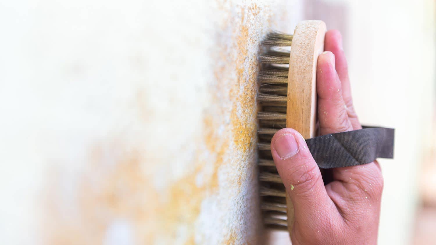 A man scrubing a wall with a wire brush