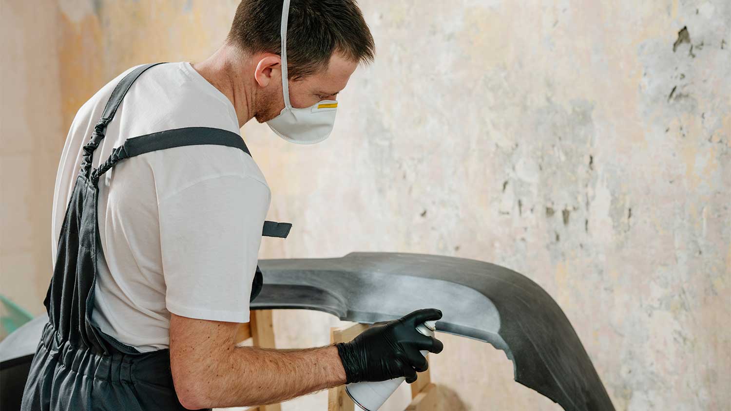 A man spray paints an object black
