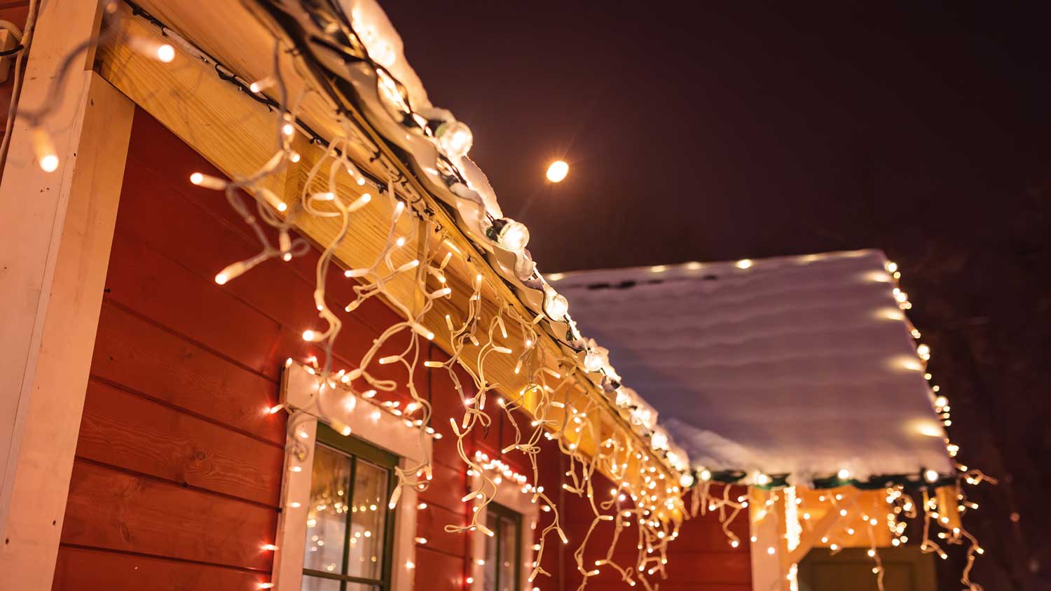 Christmas lights on the exterior of a snow covered house