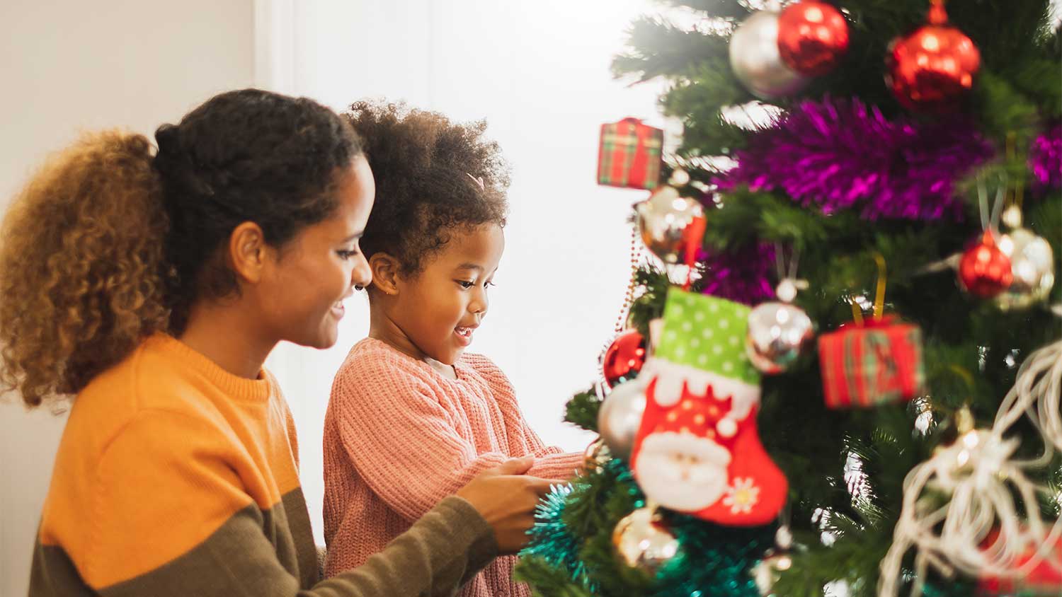 A mother and daughter decorate a christmas tree
