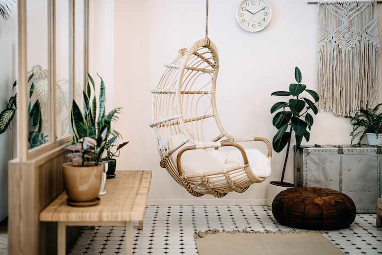 home interior with white, cream, and light wood bohemian decor with hanging chair in middle