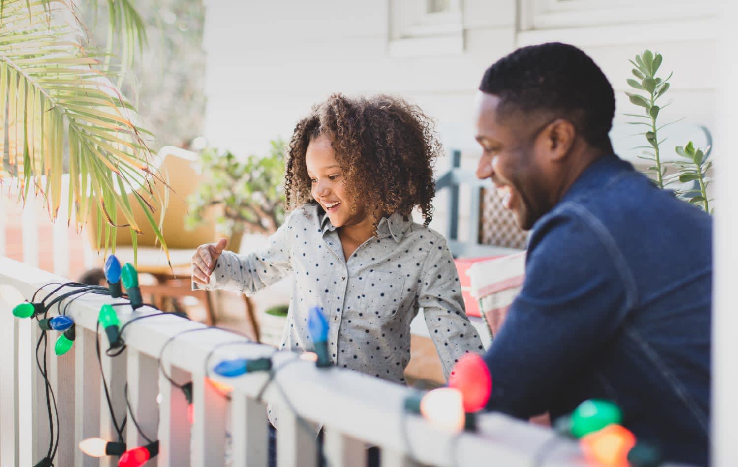 A father and his daughter hanging Christmas lights outdoors