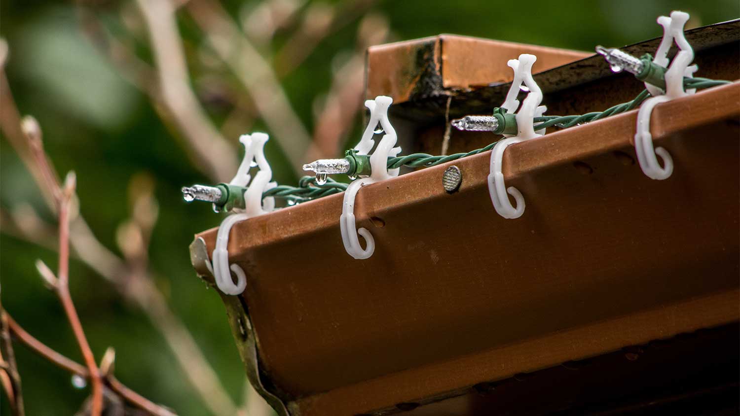 A closeup of gutter clips with Christmas lights