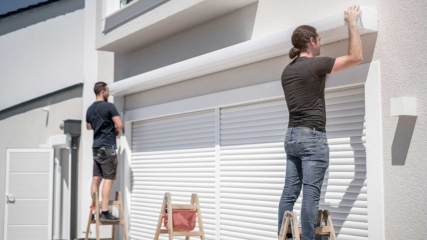 Workers standing on ladders installing an awning