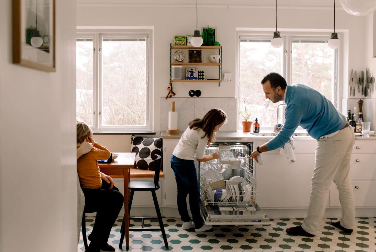 Father and daughter arranging utensils in dishwasher at kitchen