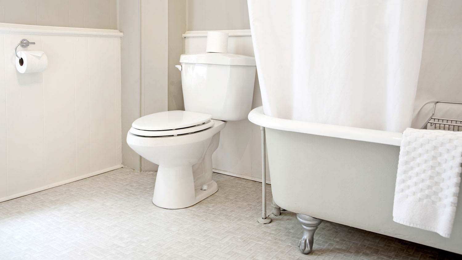 White tiled bathroom with claw foot bathtub