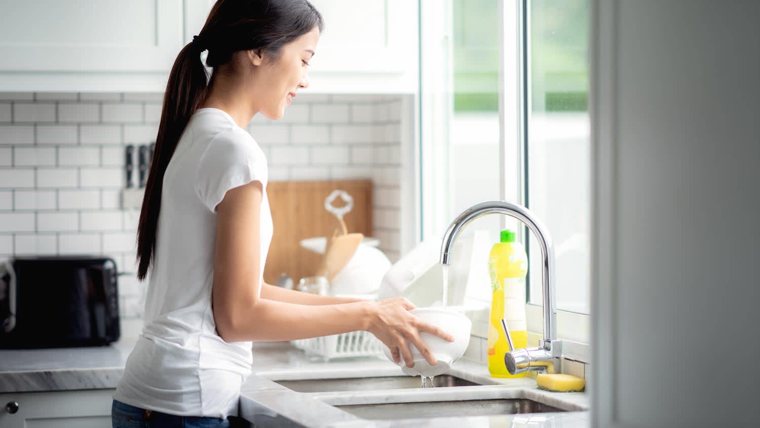 A woman washing the dishes in the kitchen sink