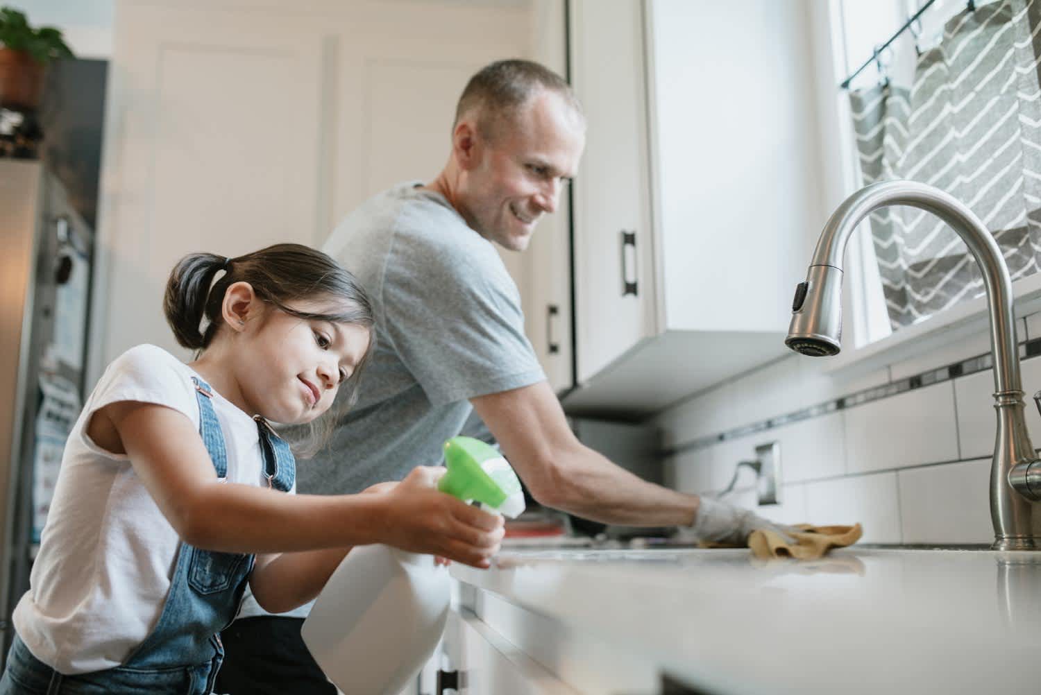 A father and his daughter cleaning their kitchen sink
