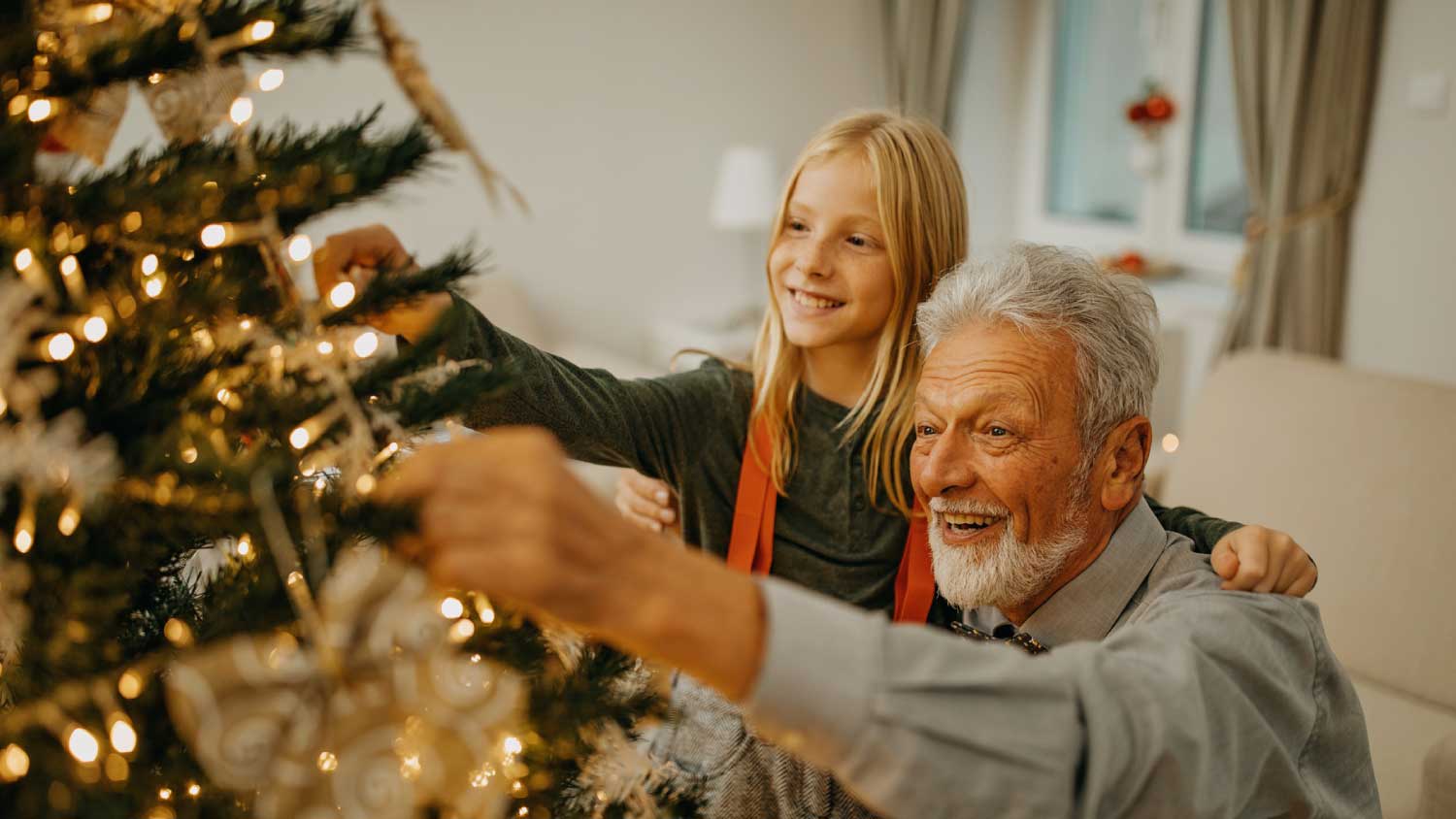 man and granddaughter decorating christmas tree