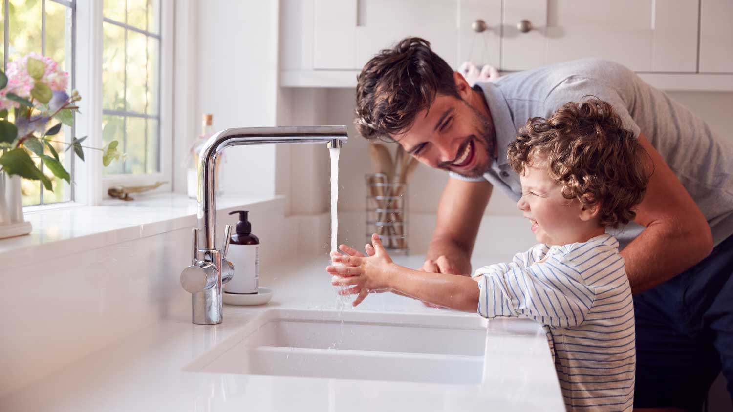 Father helping son to wash his hands