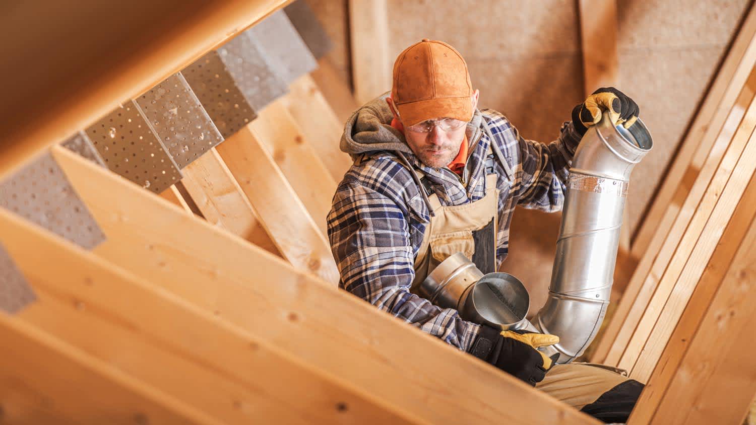 A technician installing an attic fan for ventilation