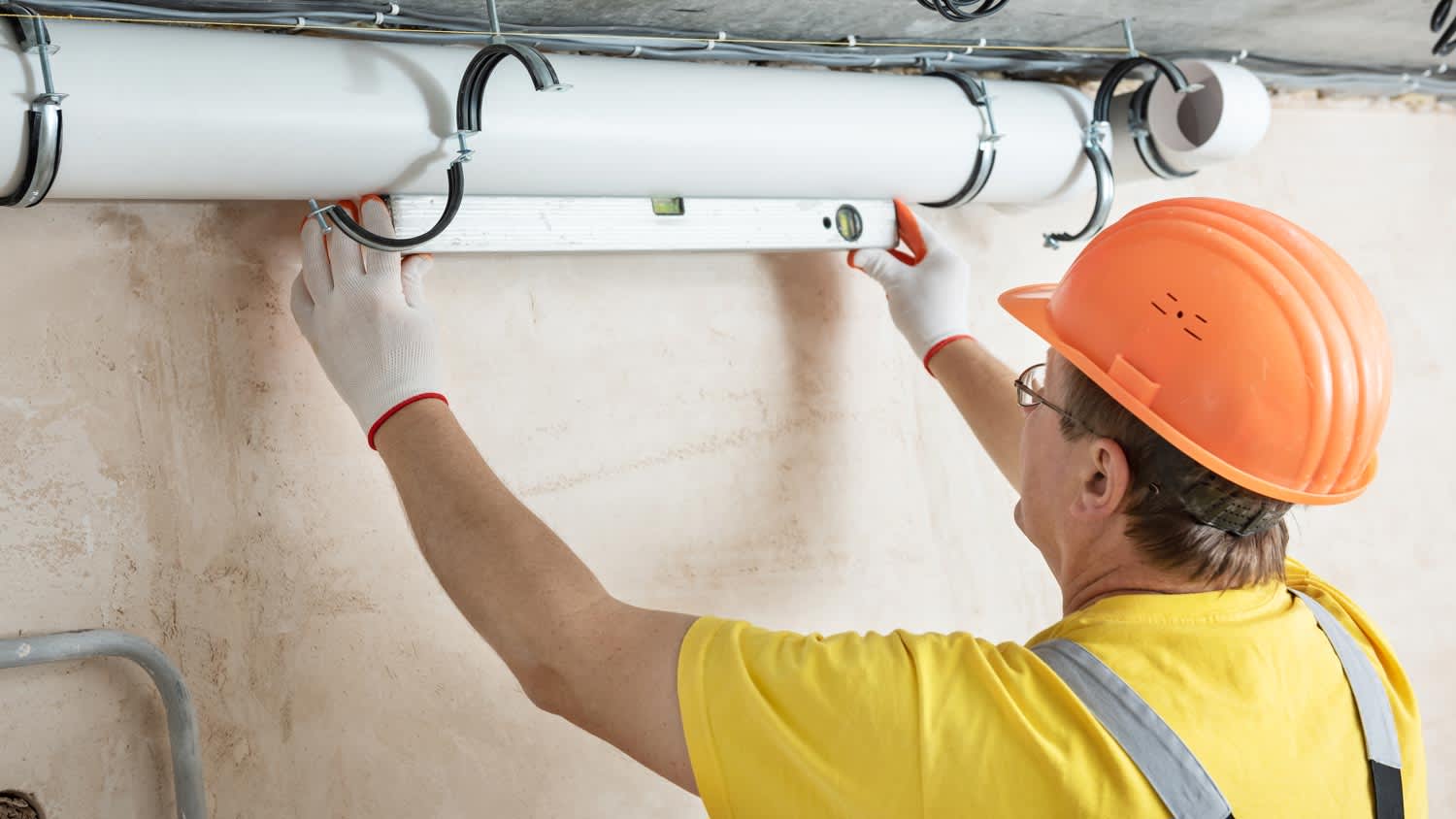 A plumber installing ventilation system pipes