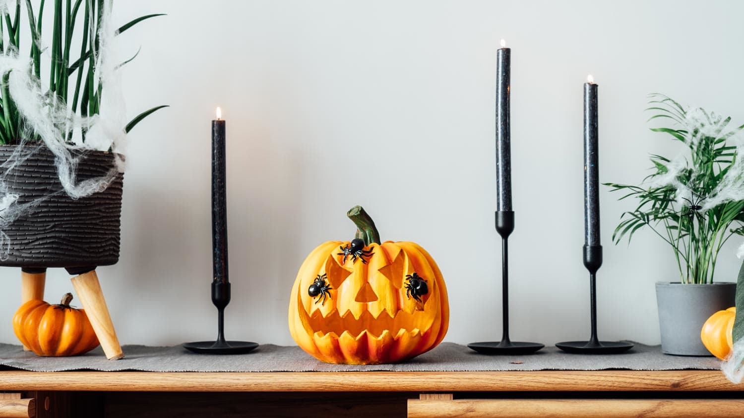 A carved pumpkin and black candles used as Halloween decoration