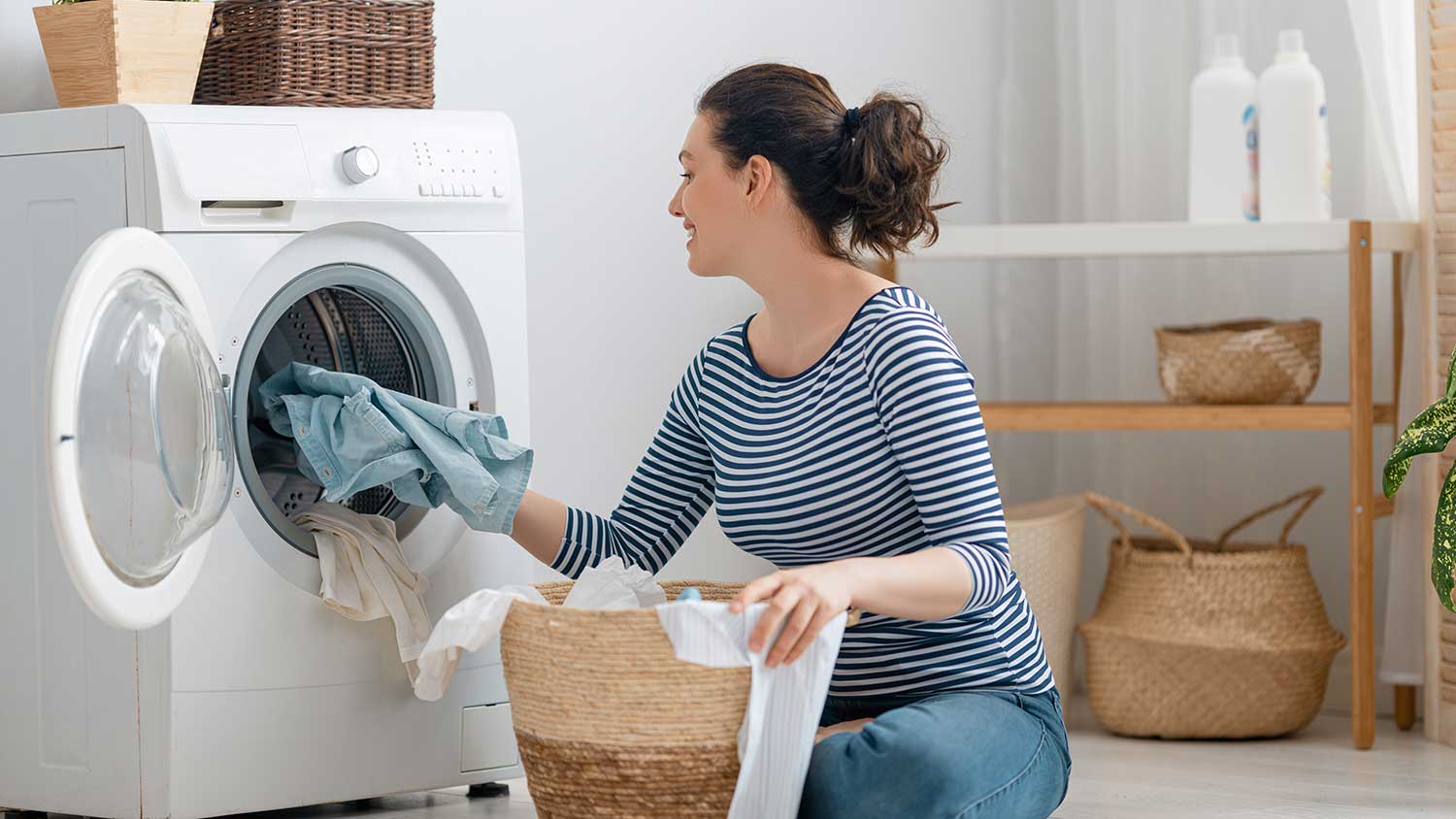 Woman at home putting dirty clothes in the washer