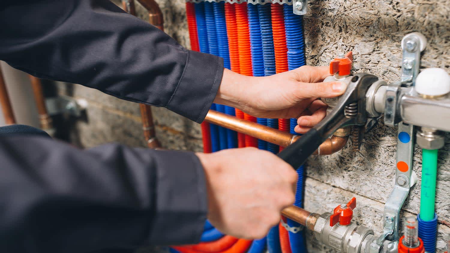 The hands of a plumber in a boiler room