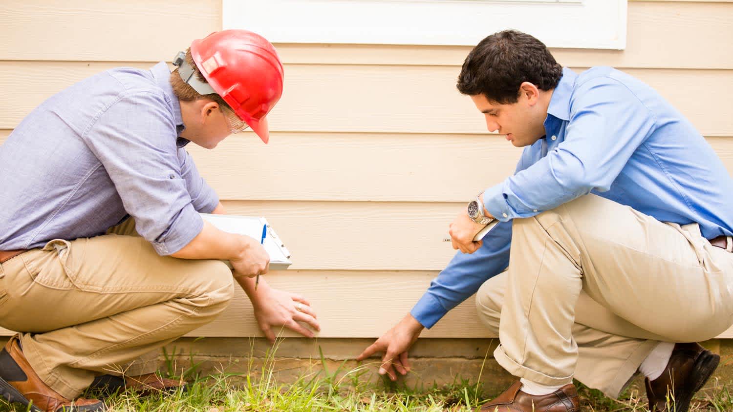 Two professionals inspecting house foundation