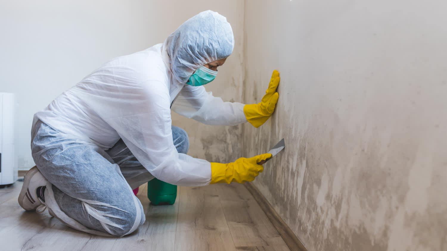 A worker removing mold using scraper tool