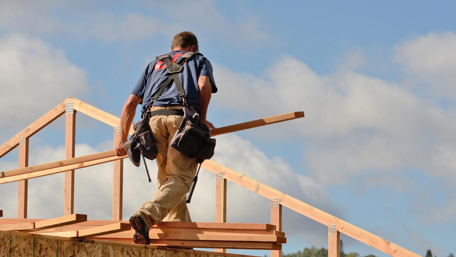 A man building a wooden roof truss