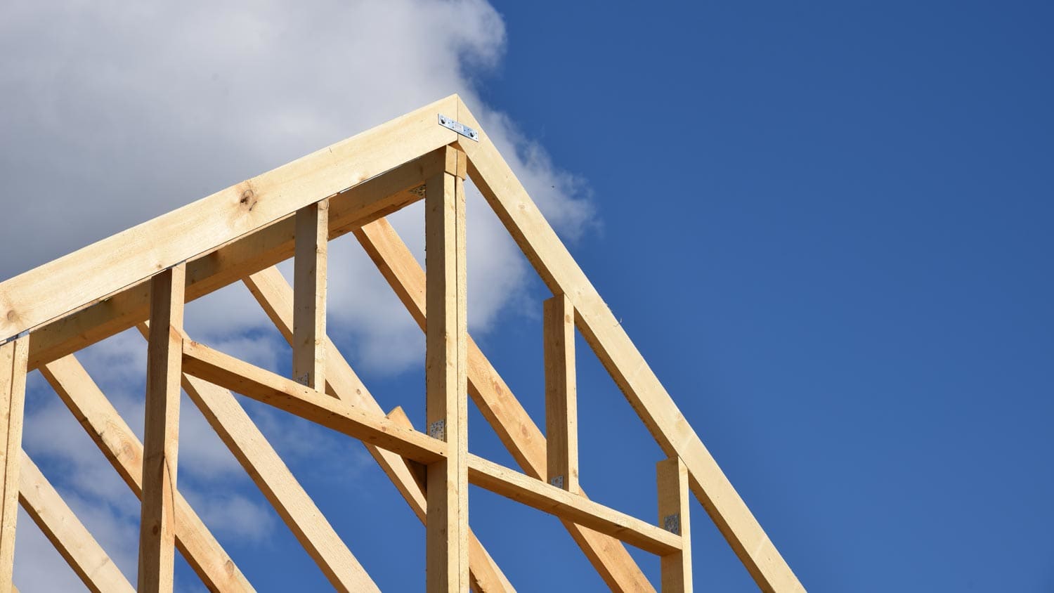 A wooden roof truss on a bright day