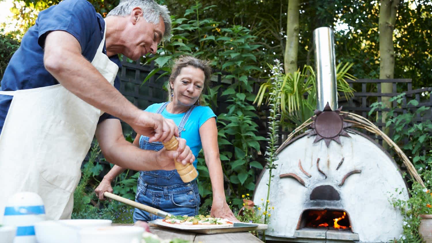 A couple cooking a pizza in the yard