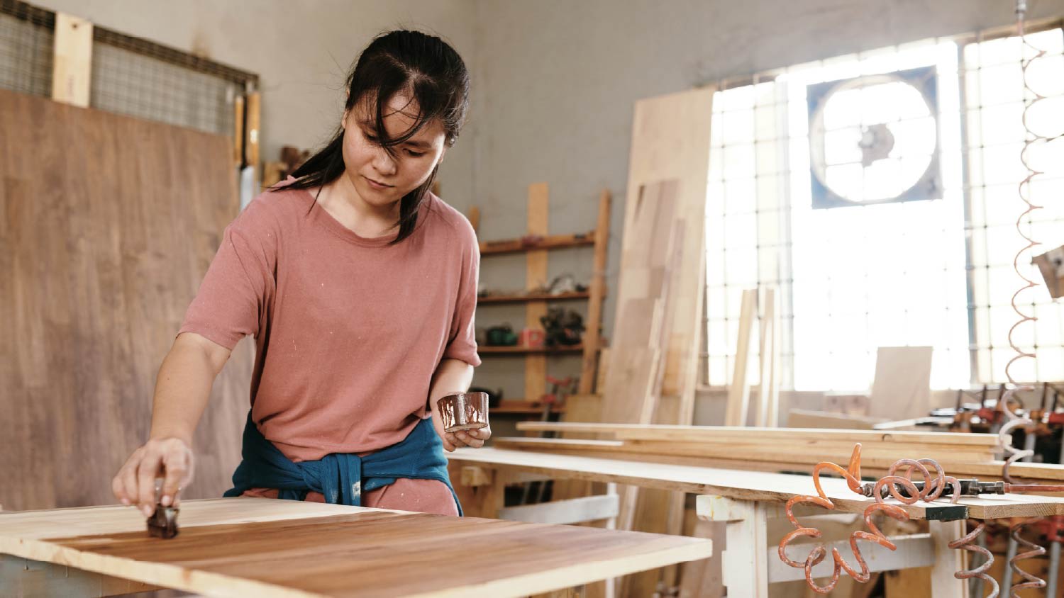 Female carpenter applying oil finish on a wooden board