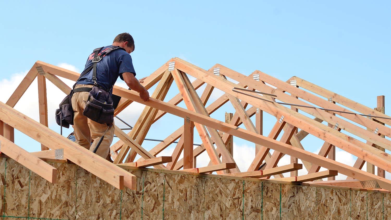 Man building wooden frame on roof.