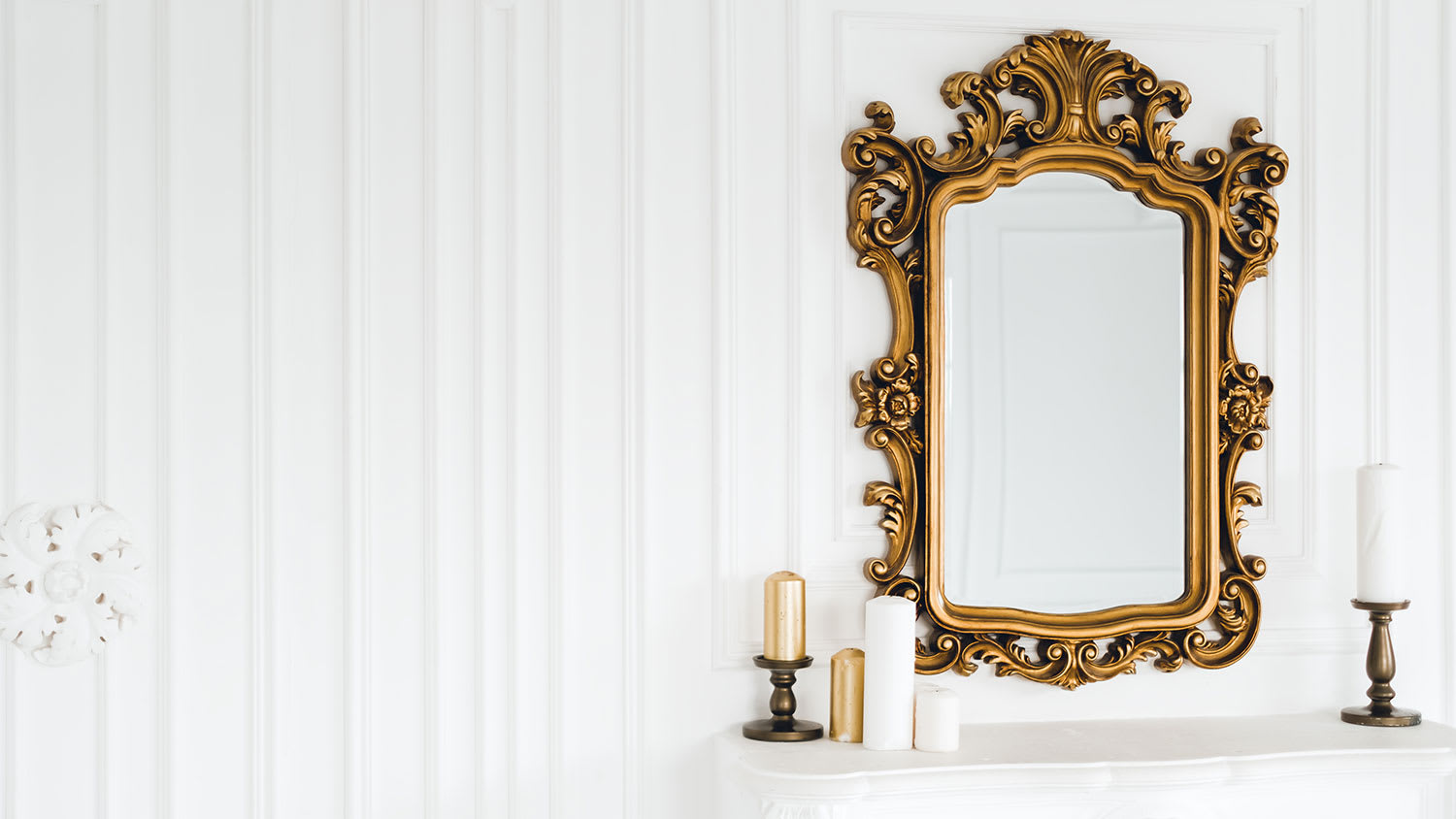 A view of an ornate gold mirror hanging on a wall