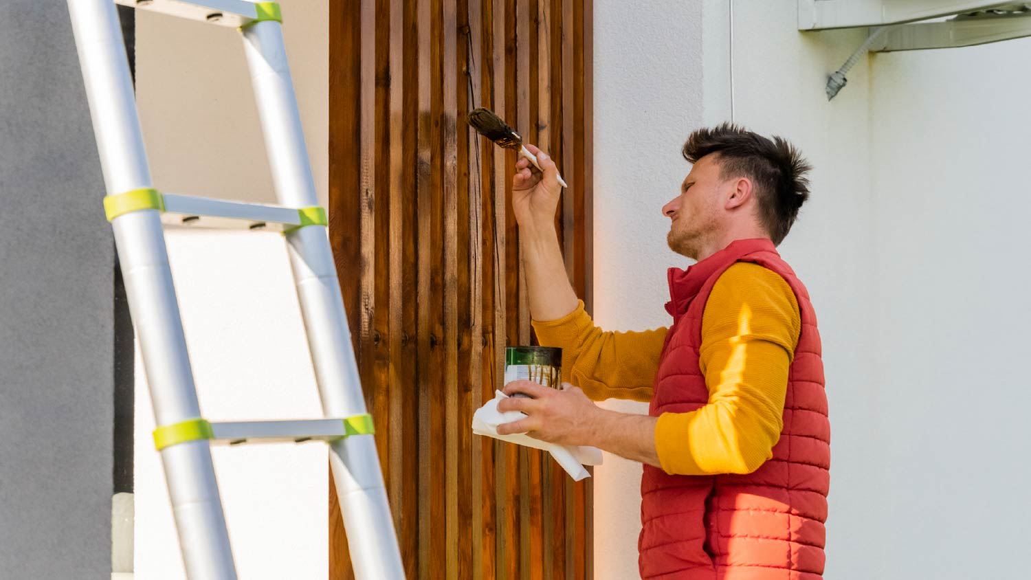Man painting wooden columns of a modern villa