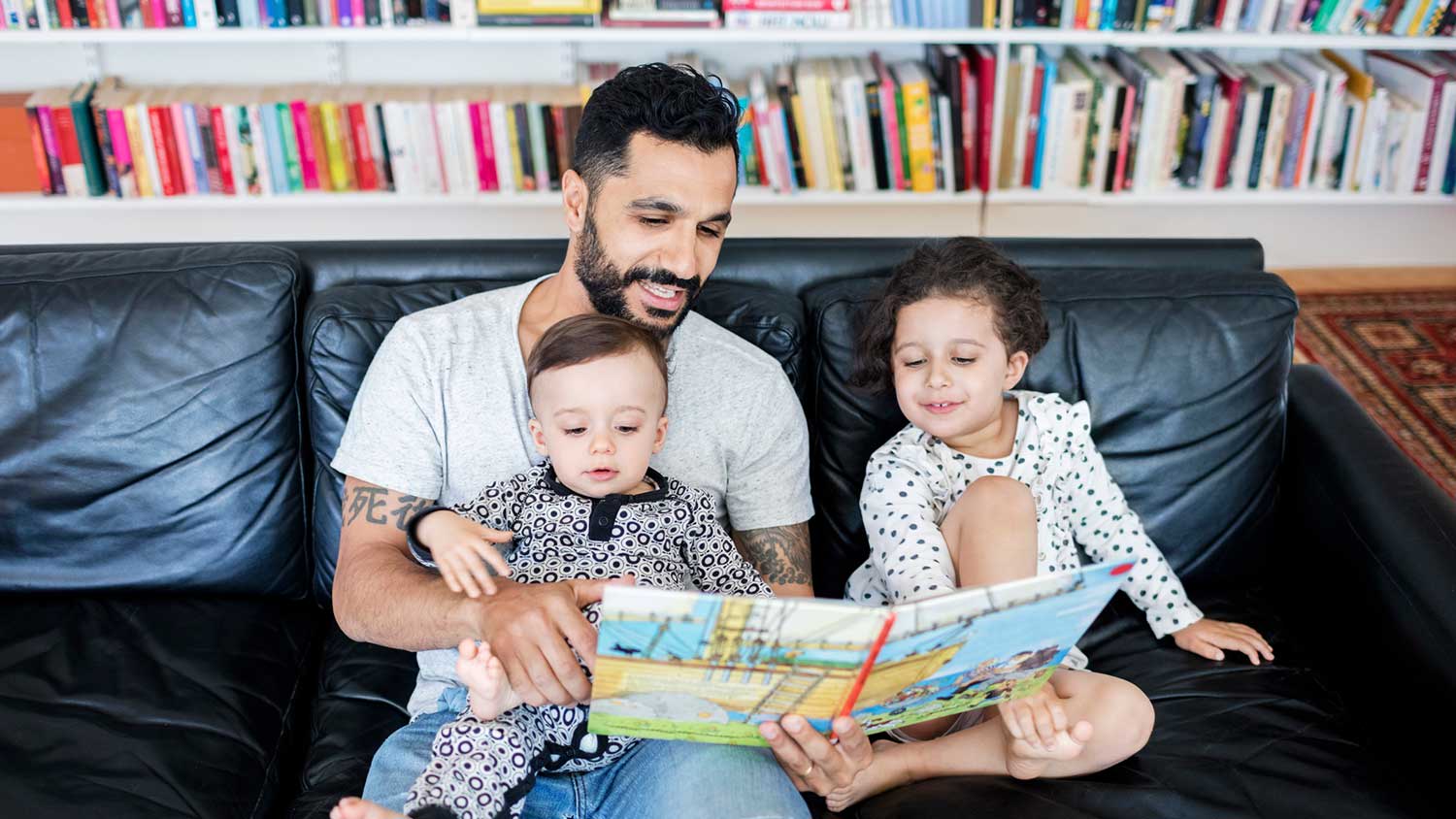 Father reading a book to the children at home