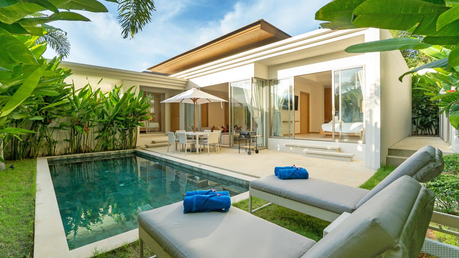 The backyard of a house with a pool in a lush garden