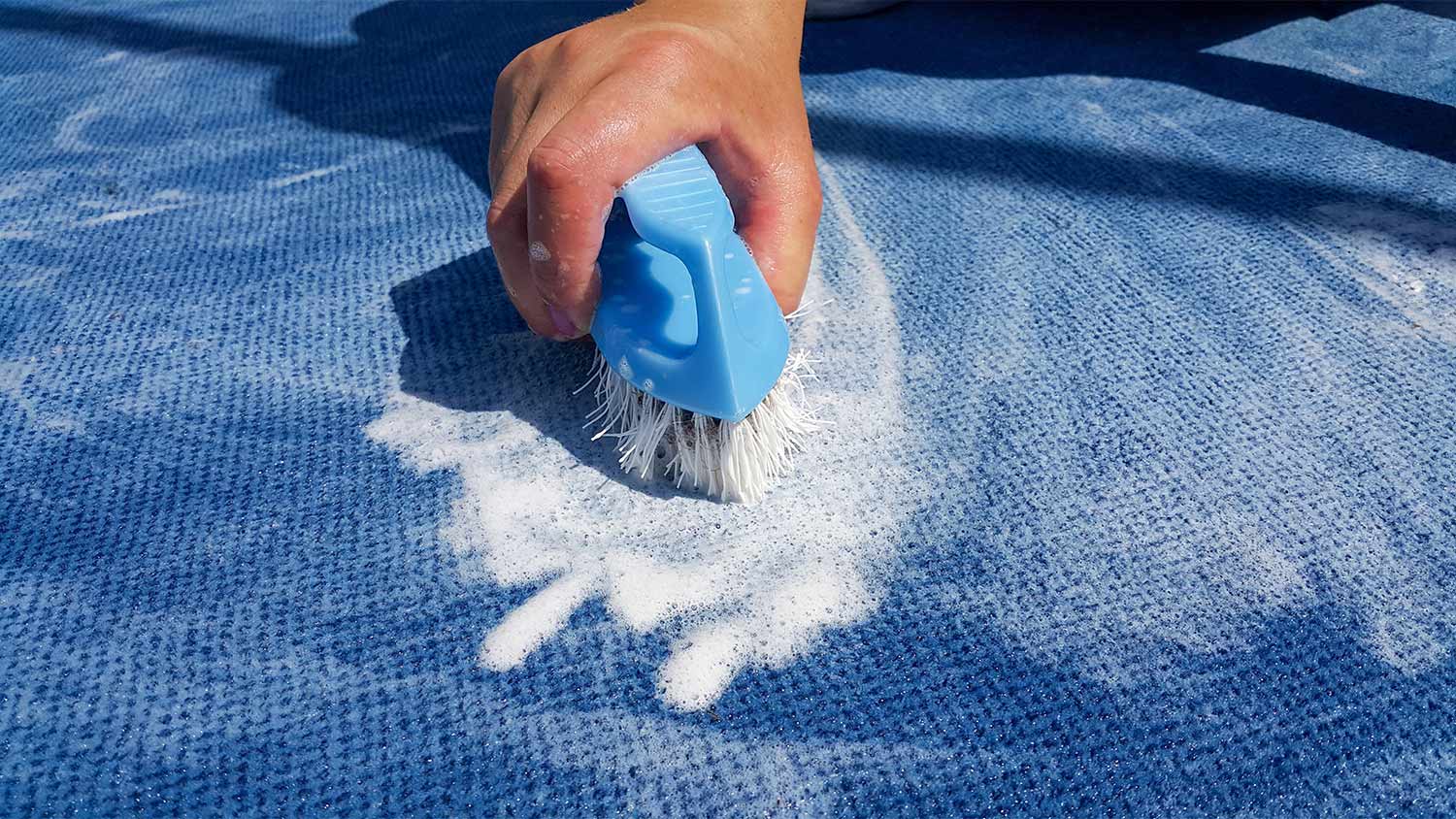 Blue carpet being cleaned by brush.