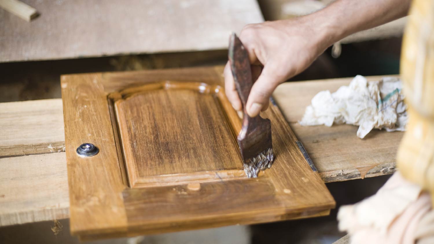 Man painting a wooden cabinet door with paintbrush