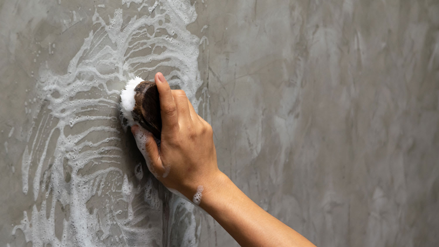 A woman handwashing a wall using a sponge
