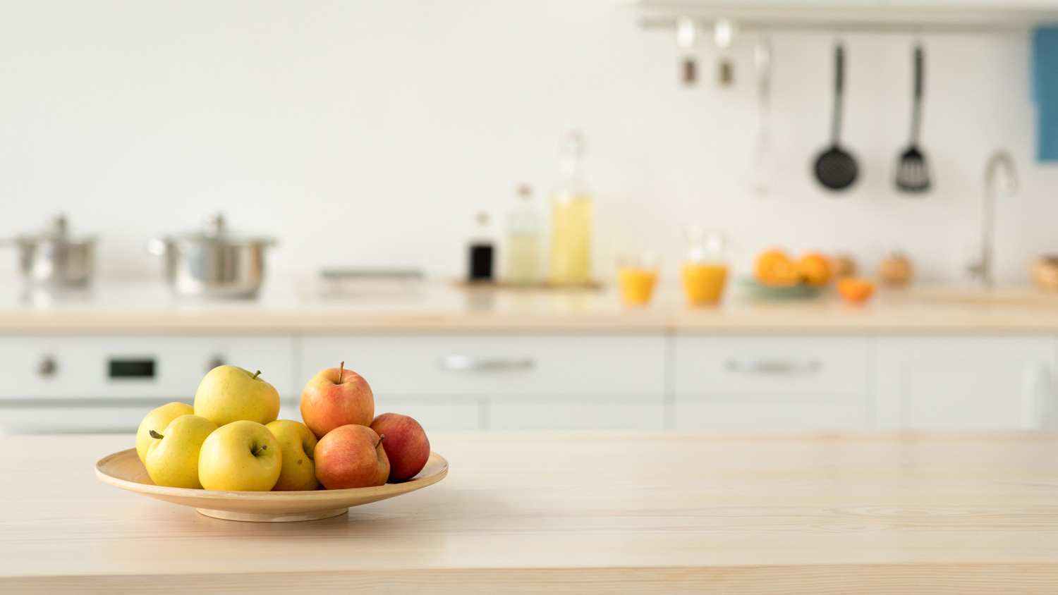 Apples placed in a wooden bowl on a kitchen countertop