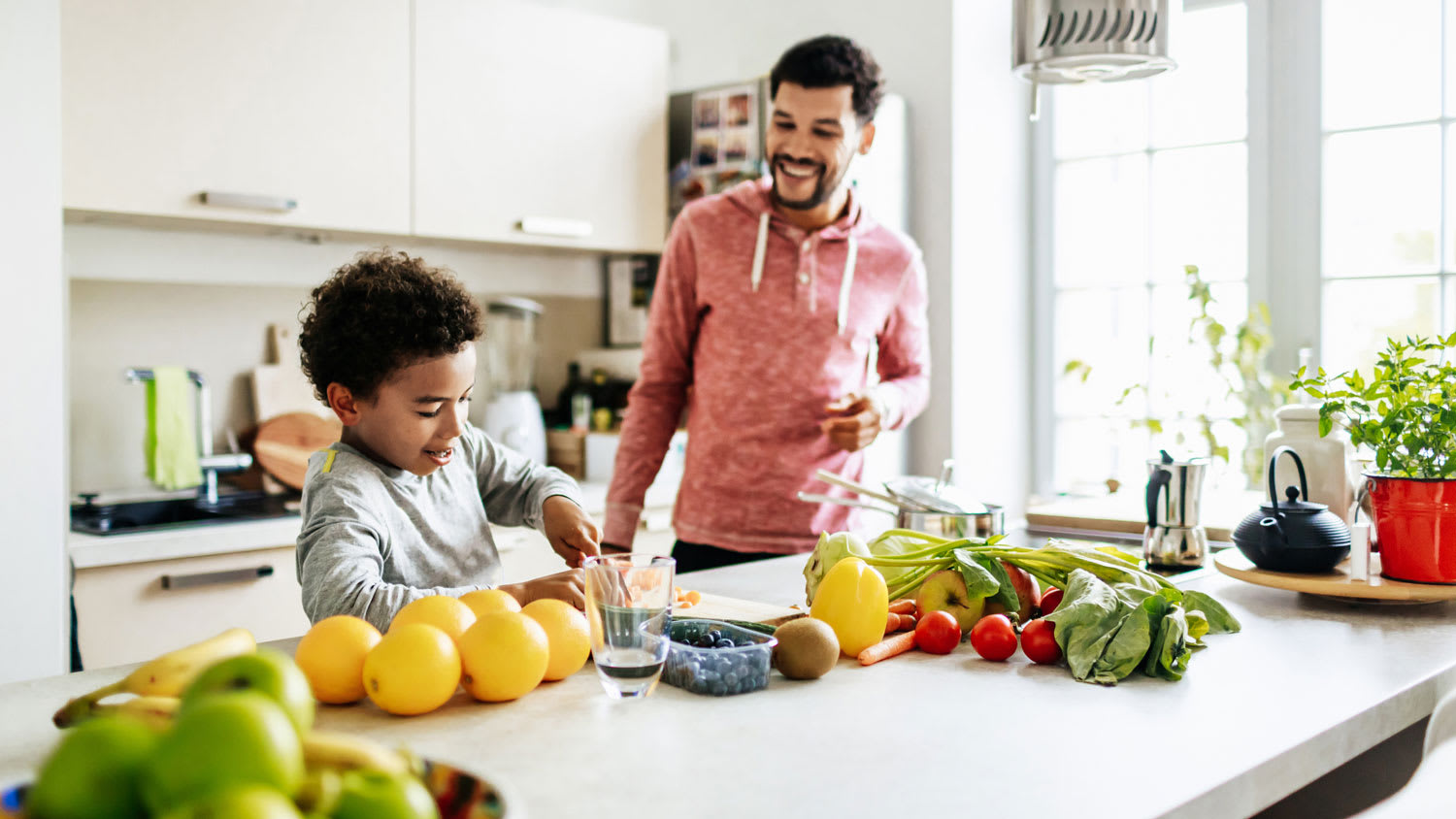 A boy and his father preparing juice in the kitchen