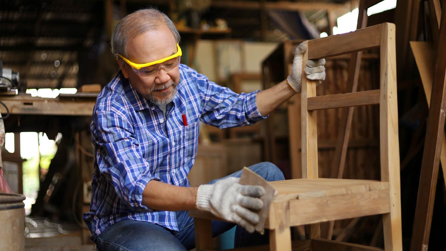 Carpenter man sanding a wooden chair