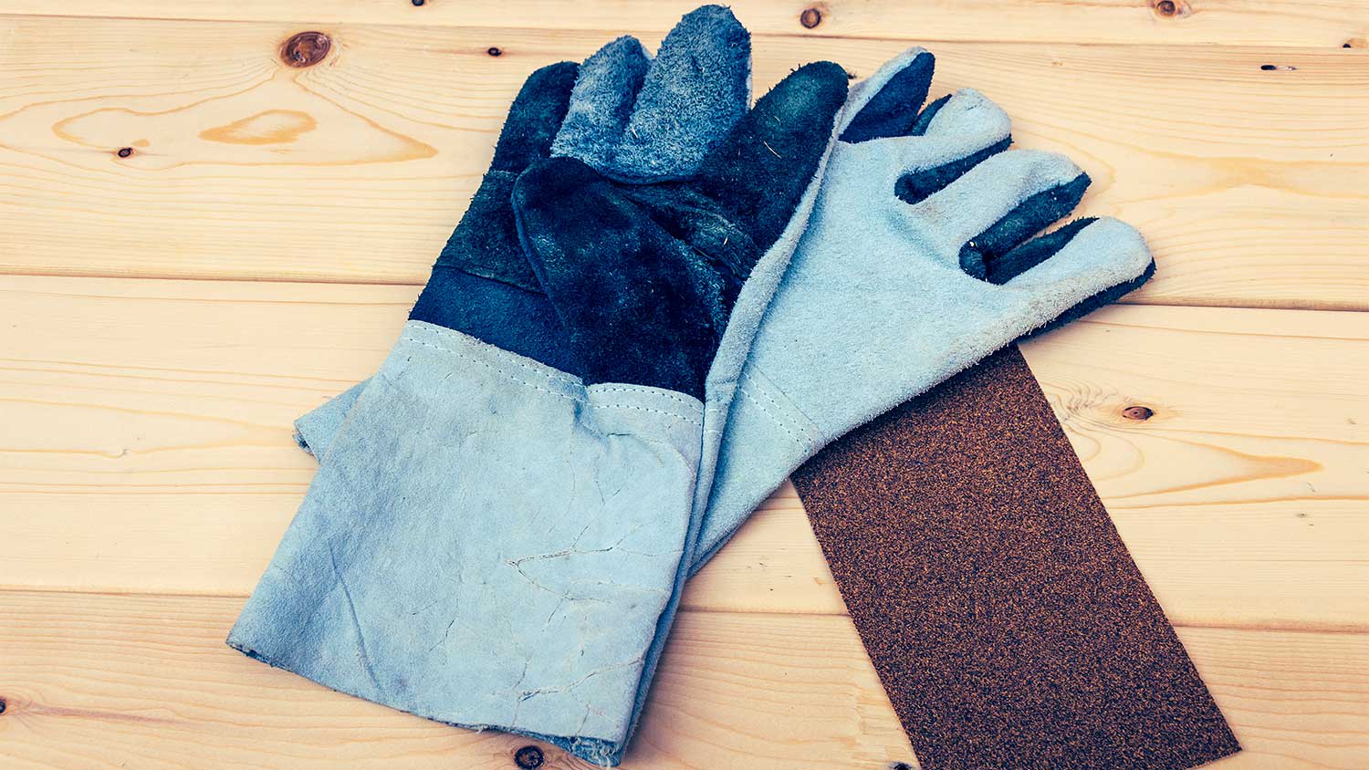 A view of work gloves and sandpaper on a table