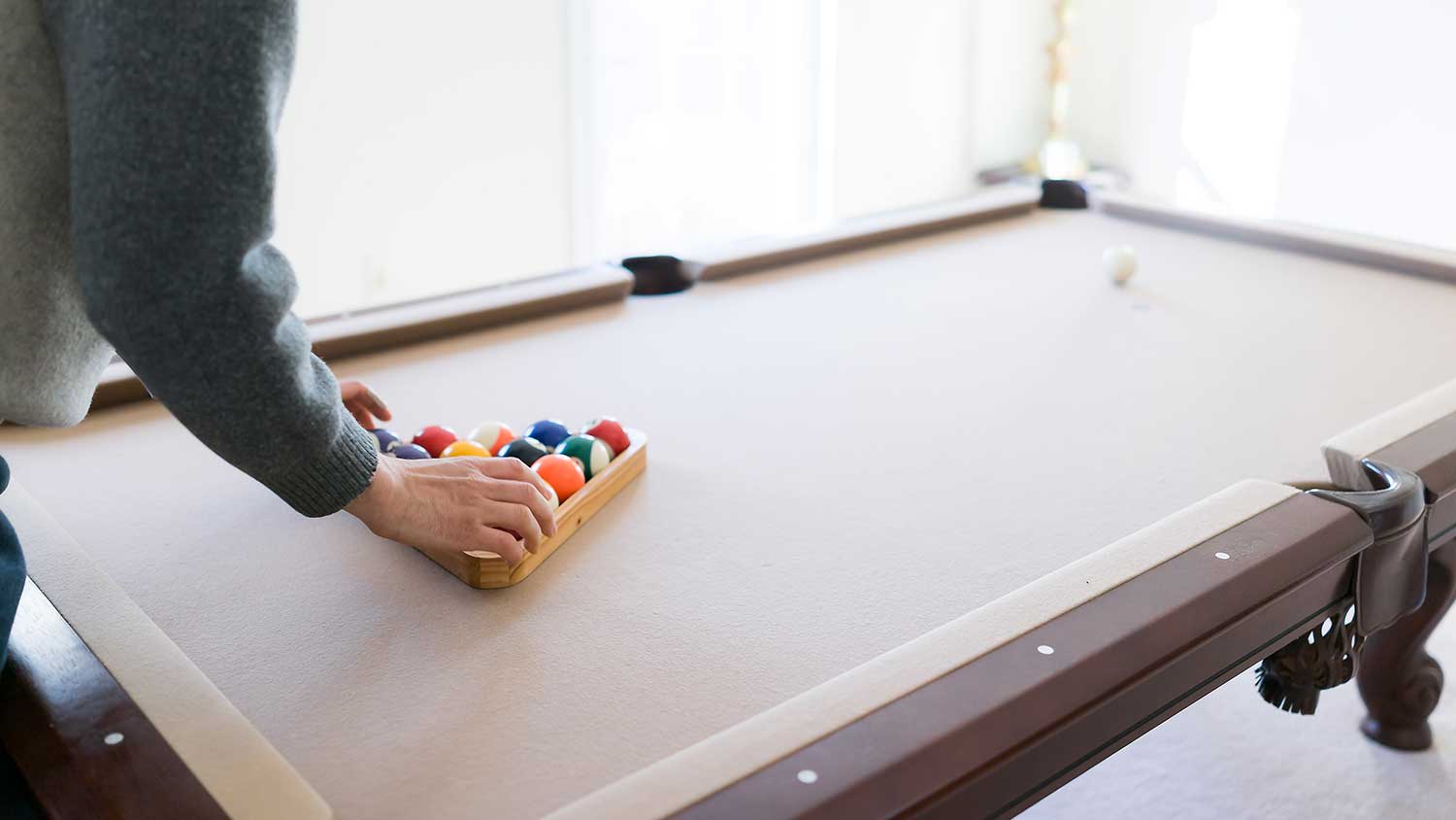 Person setting up tan pool table