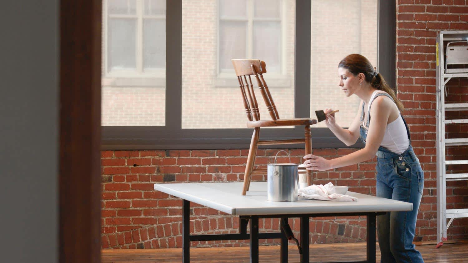 Woman painting chair in loft