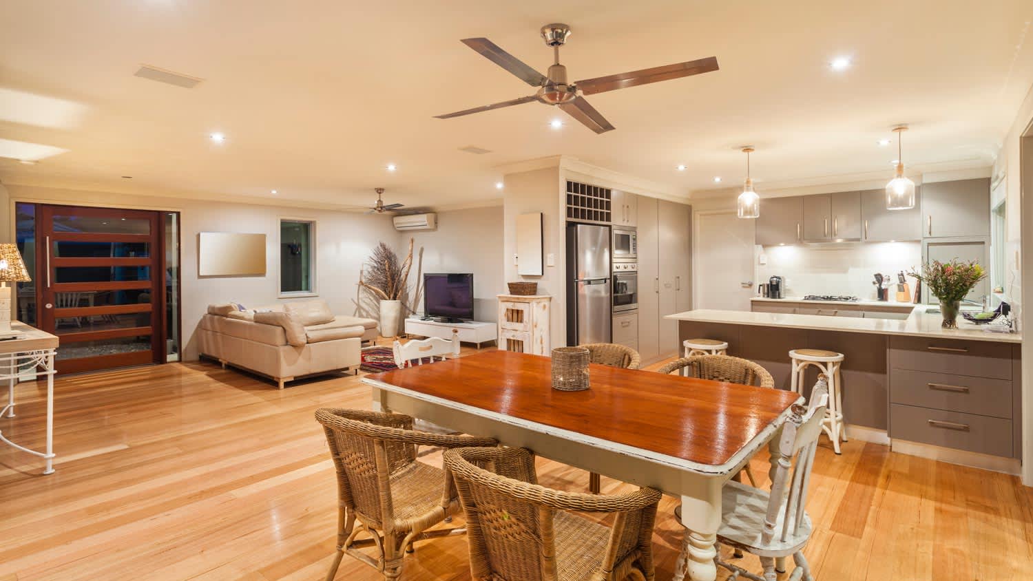 An open space living room with a ceiling fan above the dining area