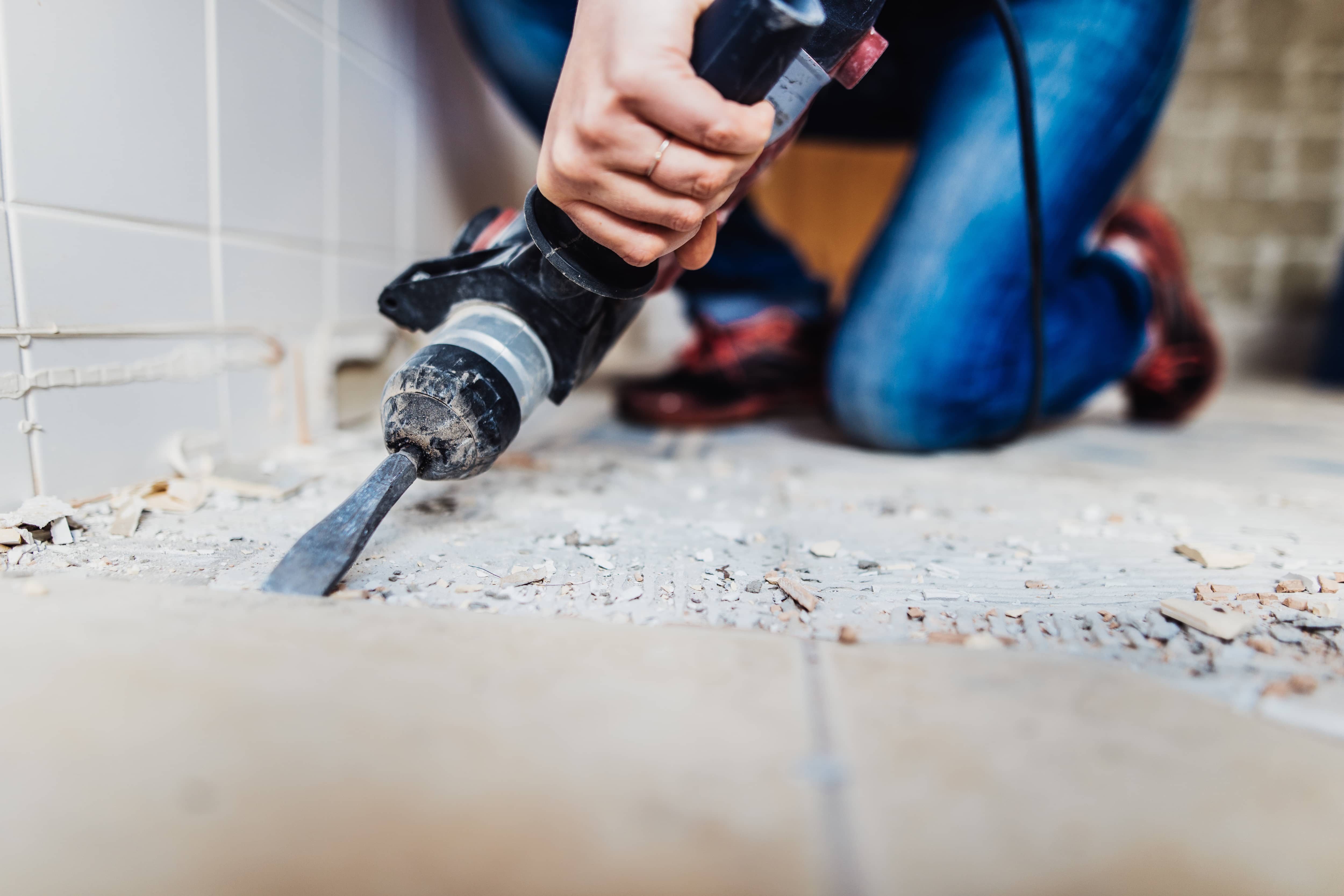 A person removing tile flooring with a power chisel