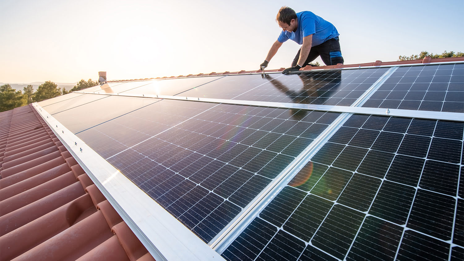 Man installing solar panels on roof.
