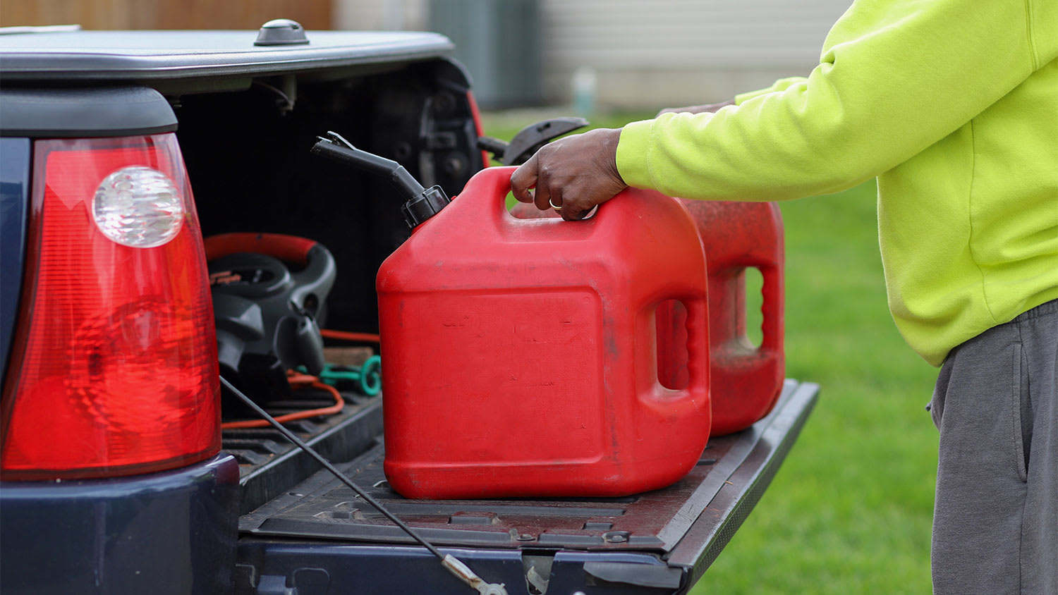 man holding red plastic gas tanks