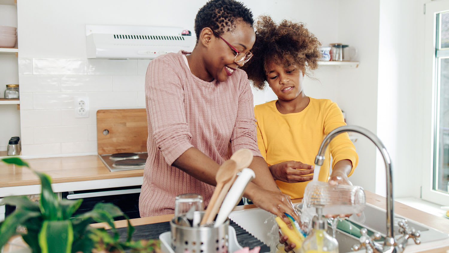 Girl helping mom wash the dishes at home