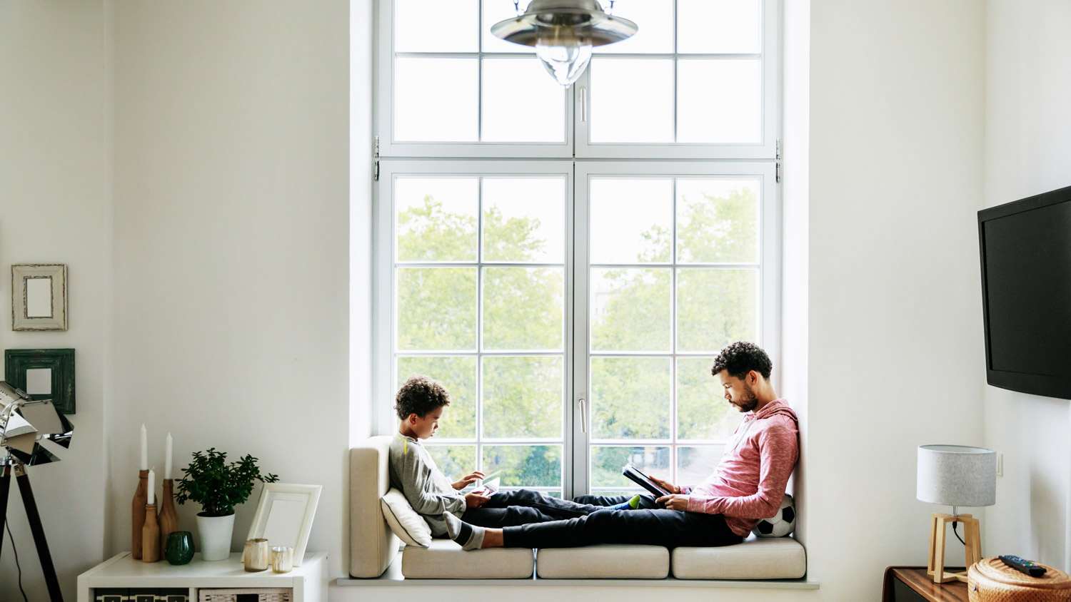 A father and son sitting by the window reading their books