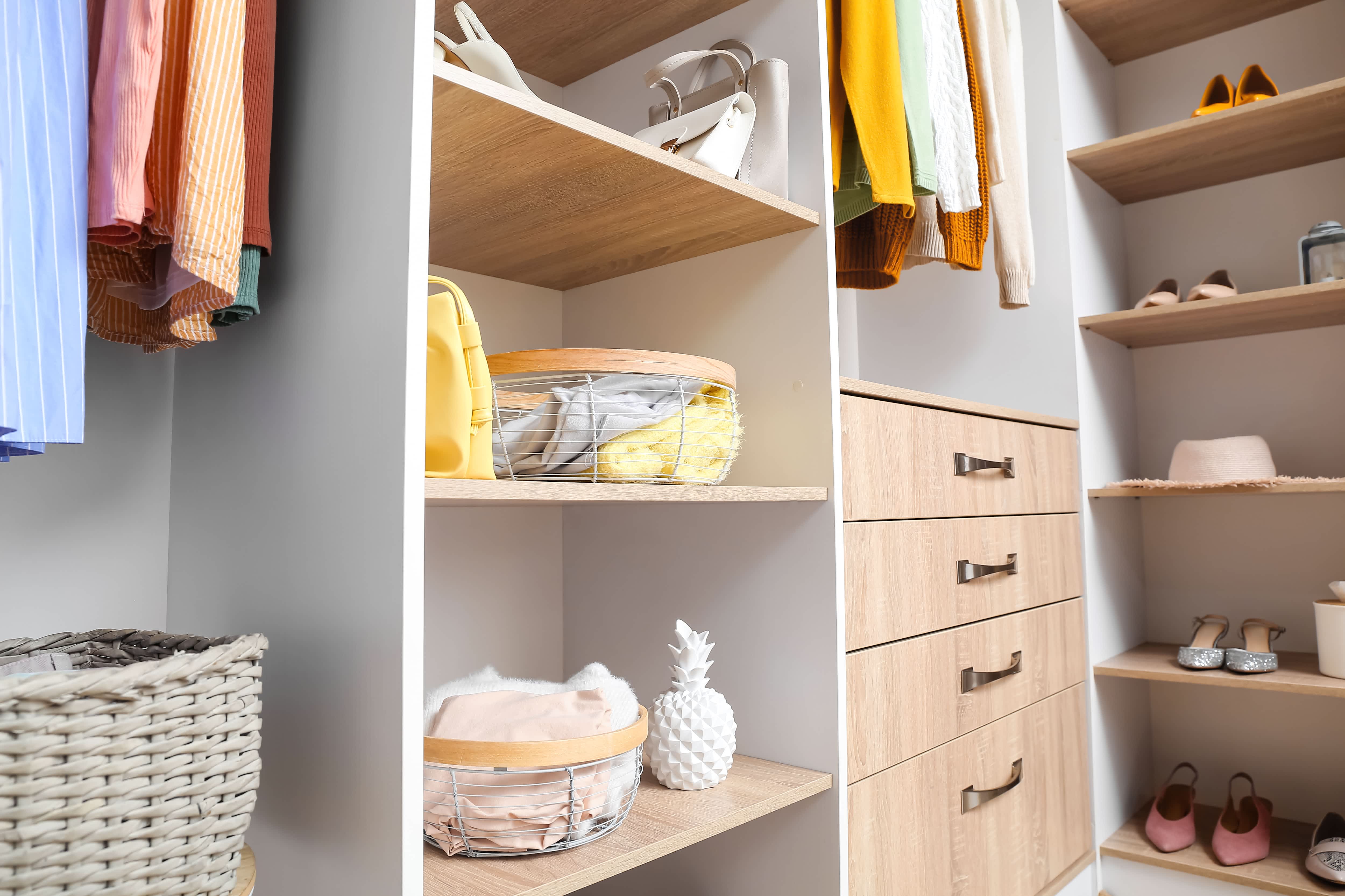 A small walk-in closet with shelving system and dresser