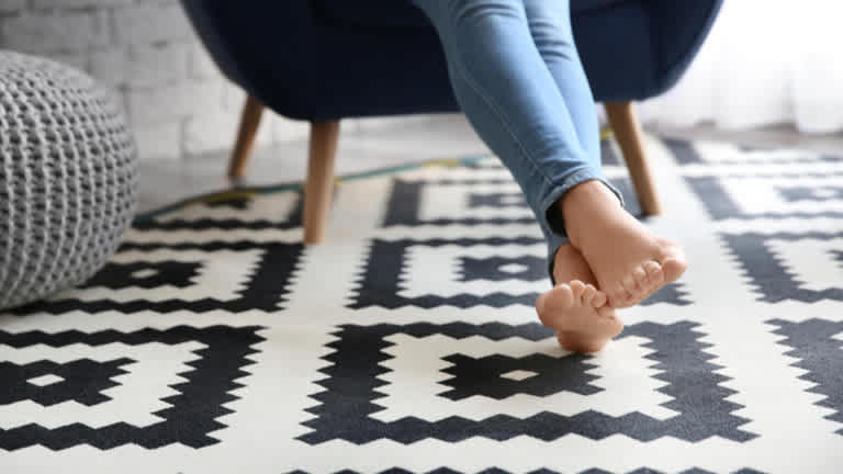Woman in armchair resting feet on patterned carpet