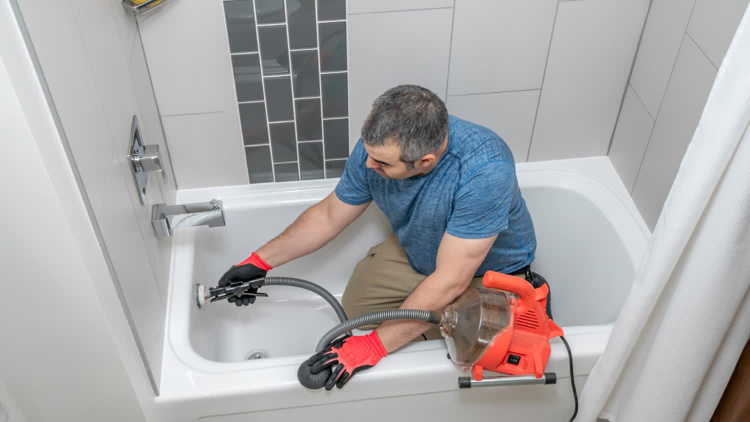 A plumber cleaning a bathtub