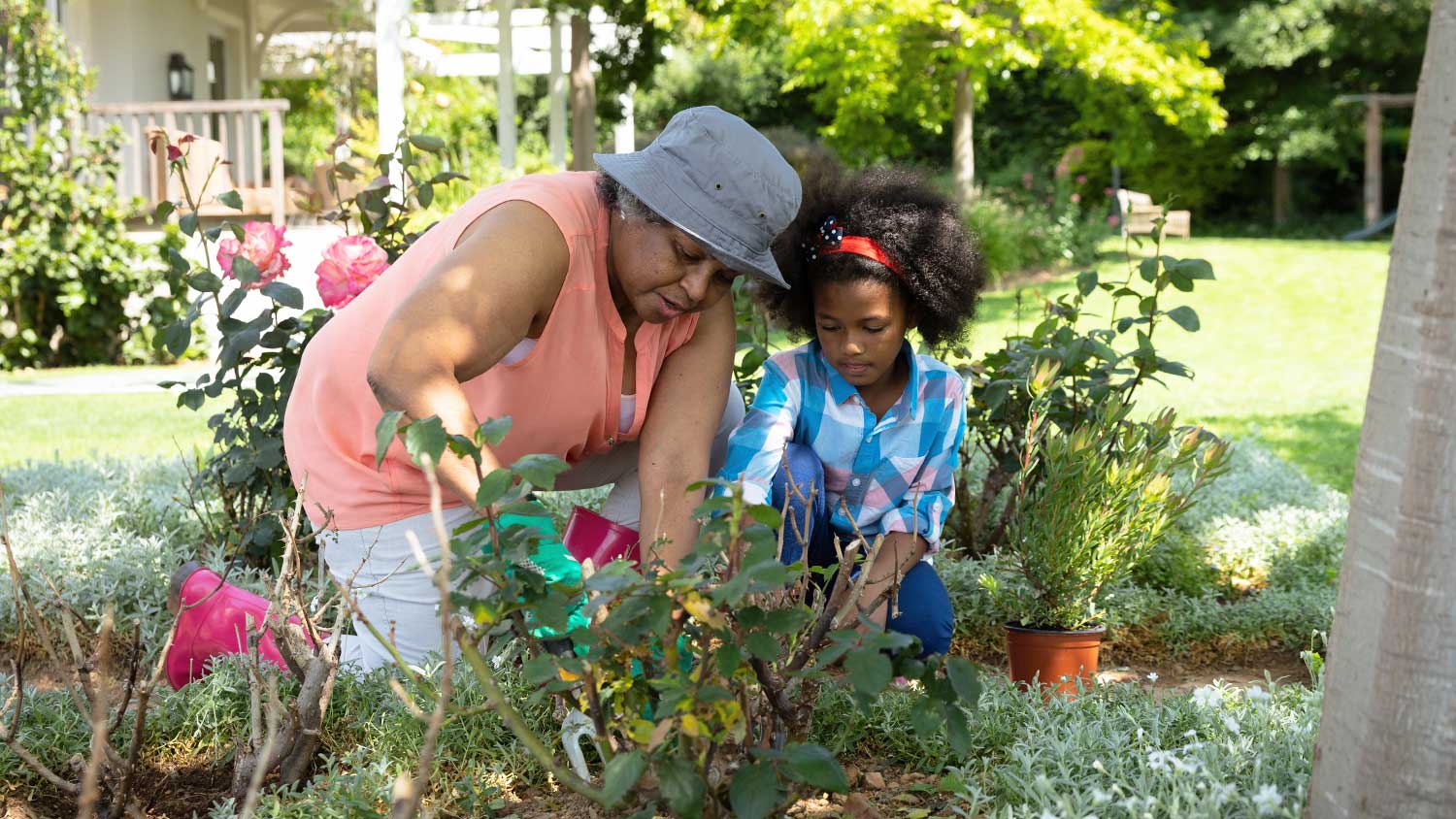 Grandmother teaching granddaughter how to garden