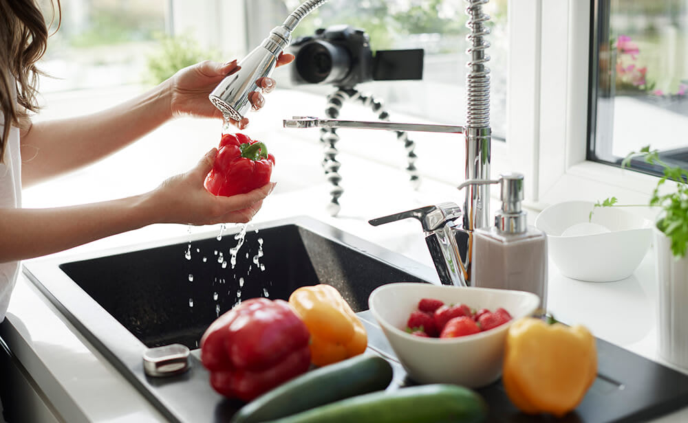 Modern kitchen sink with person washing vegetables